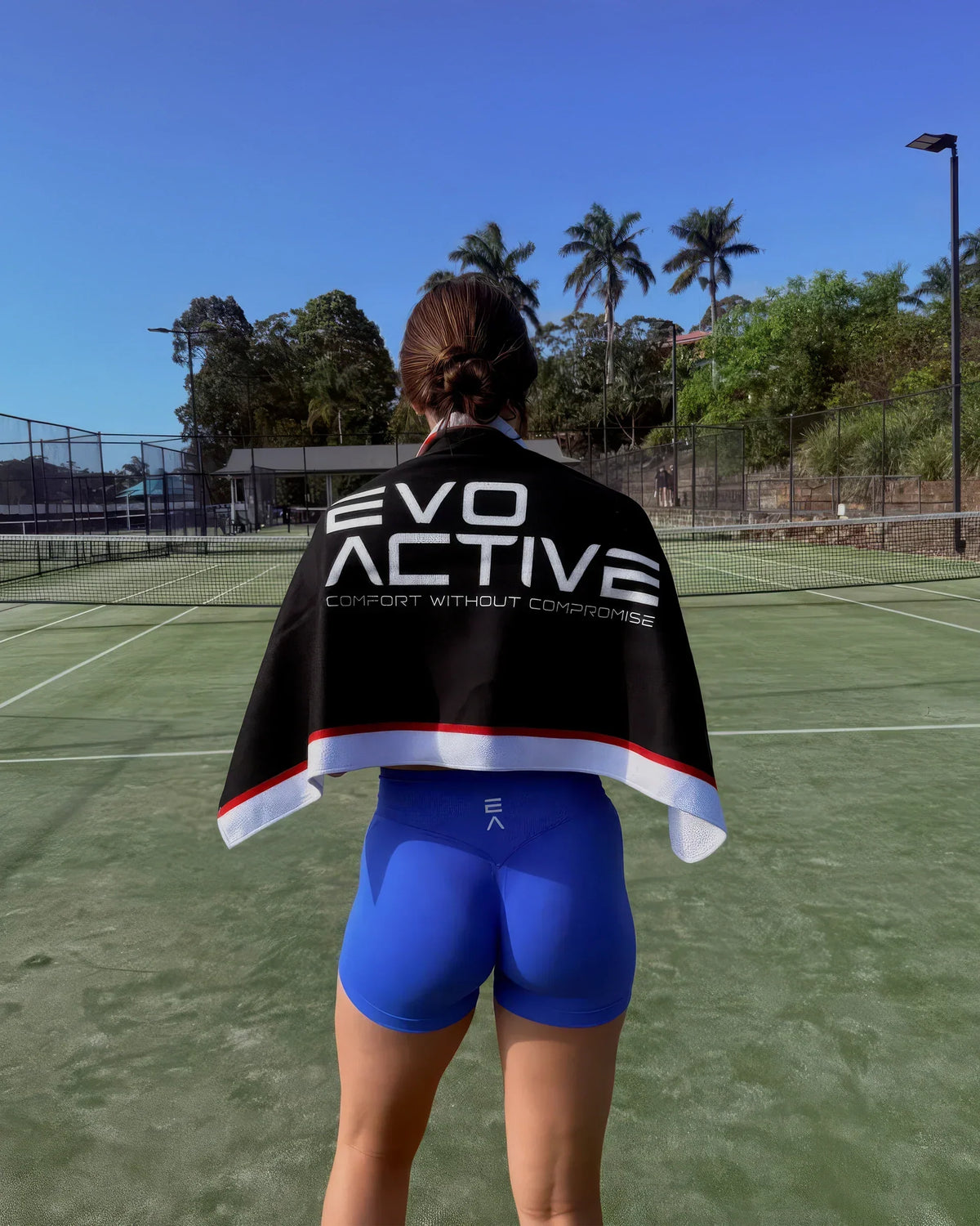 Woman holding EVOActive gym towel during workout on training field