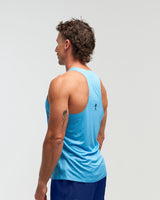 Side pose with back visible of man wearing ocean blue EVOActive Men’s Aero Singlet with logo visible against a bright background