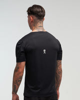 Back view of man wearing midnight black EVOActive Men’s Aero Tee with logo visible against a bright background