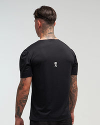 Back view of man wearing midnight black EVOActive Men’s Aero Tee with logo visible against a bright background