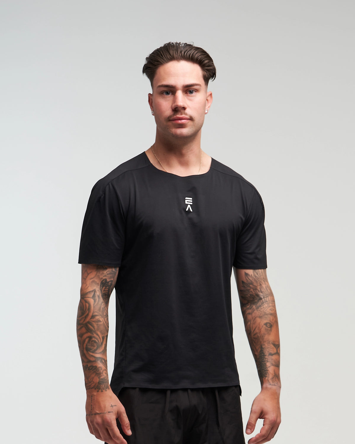 Front view of man wearing midnight black EVOActive Men’s Aero Tee with logo visible against a bright background