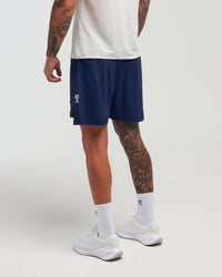 Back view of man wearing eclipse navy EVOActive Men’s FlexMotion Shorts with logo visible on the shorts against a bright background
