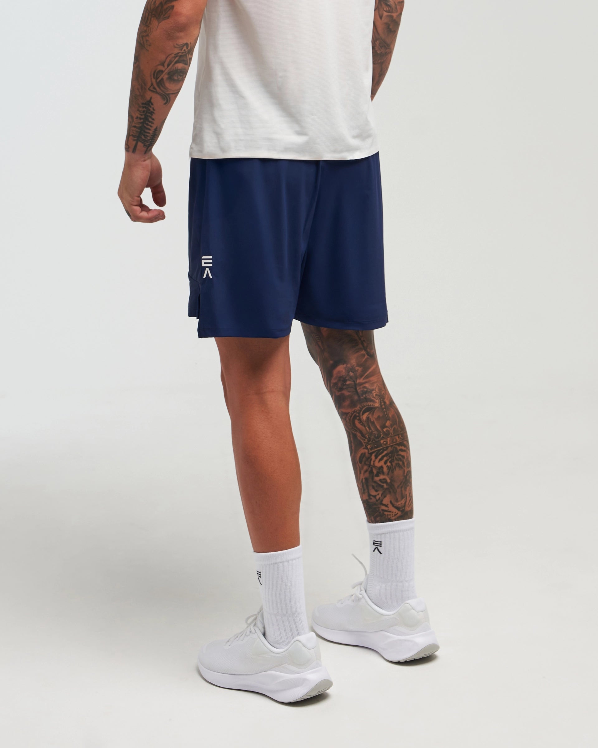 Back view of man wearing eclipse navy EVOActive Men’s FlexMotion Shorts with logo visible on the shorts against a bright background