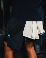 Product-focused image of man wearing EVOActive Men’s FlexMotion Shorts with logo visible in a gym setting
