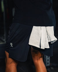 Product-focused image of man wearing EVOActive Men’s FlexMotion Shorts with logo visible in a gym setting
