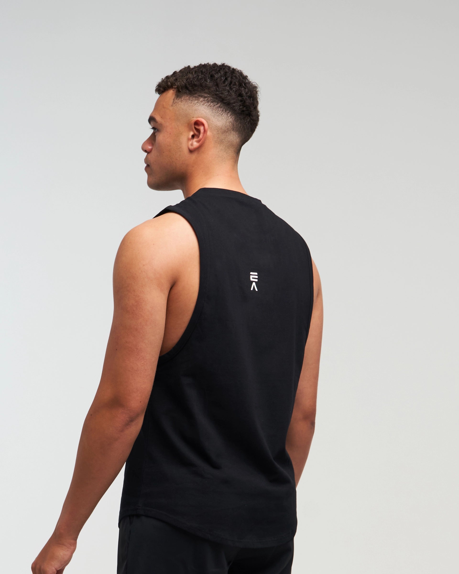 Back view of man wearing midnight black EVOActive Men’s Flex Singlet in a slight side pose with logo visible
