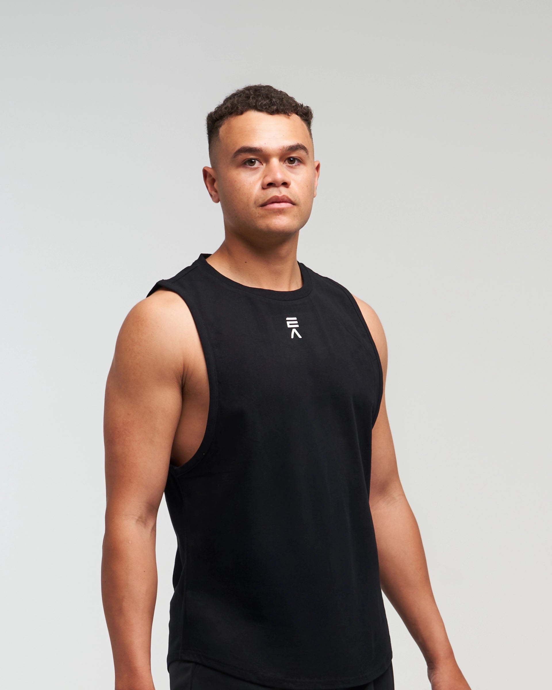 Front view of man wearing midnight black EVOActive Men’s Flex Singlet in a slight side pose with logo visible