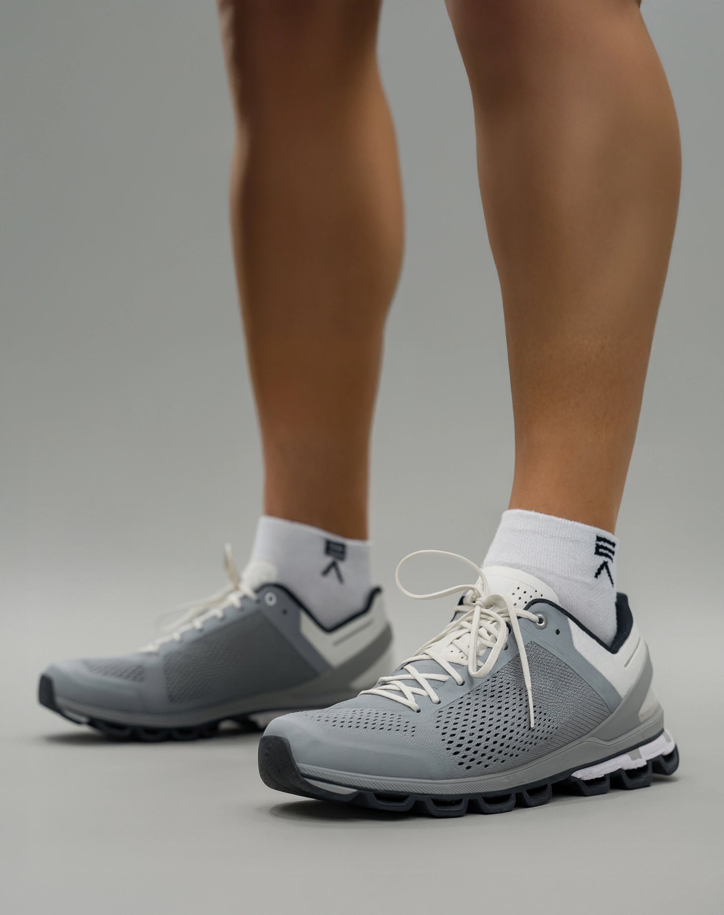 Person wearing Evo Ice white EVOActive Sprint Low Sock with logo visible, paired with grey shoes against a bright studio background