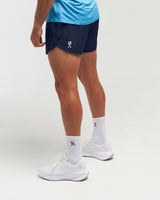 Half-body side pose with back visible of man wearing deep blue EVOActive Unisex Aero Run Short with logo visible on the shorts against a bright background