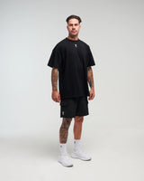 Full body view of man wearing midnight black EVOActive Unisex Classic Jogger Short with logo visible on the shorts standing against a bright background