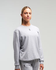 Front view of woman wearing clouded grey EVOActive Unisex Classic LS Crew Neck Tee with logo visible against a bright background