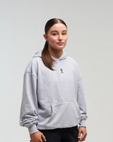 Front view of woman in a slight side pose wearing clouded grey EVOActive Unisex Classic Pullover Hoody with logo visible on the garment against a bright background