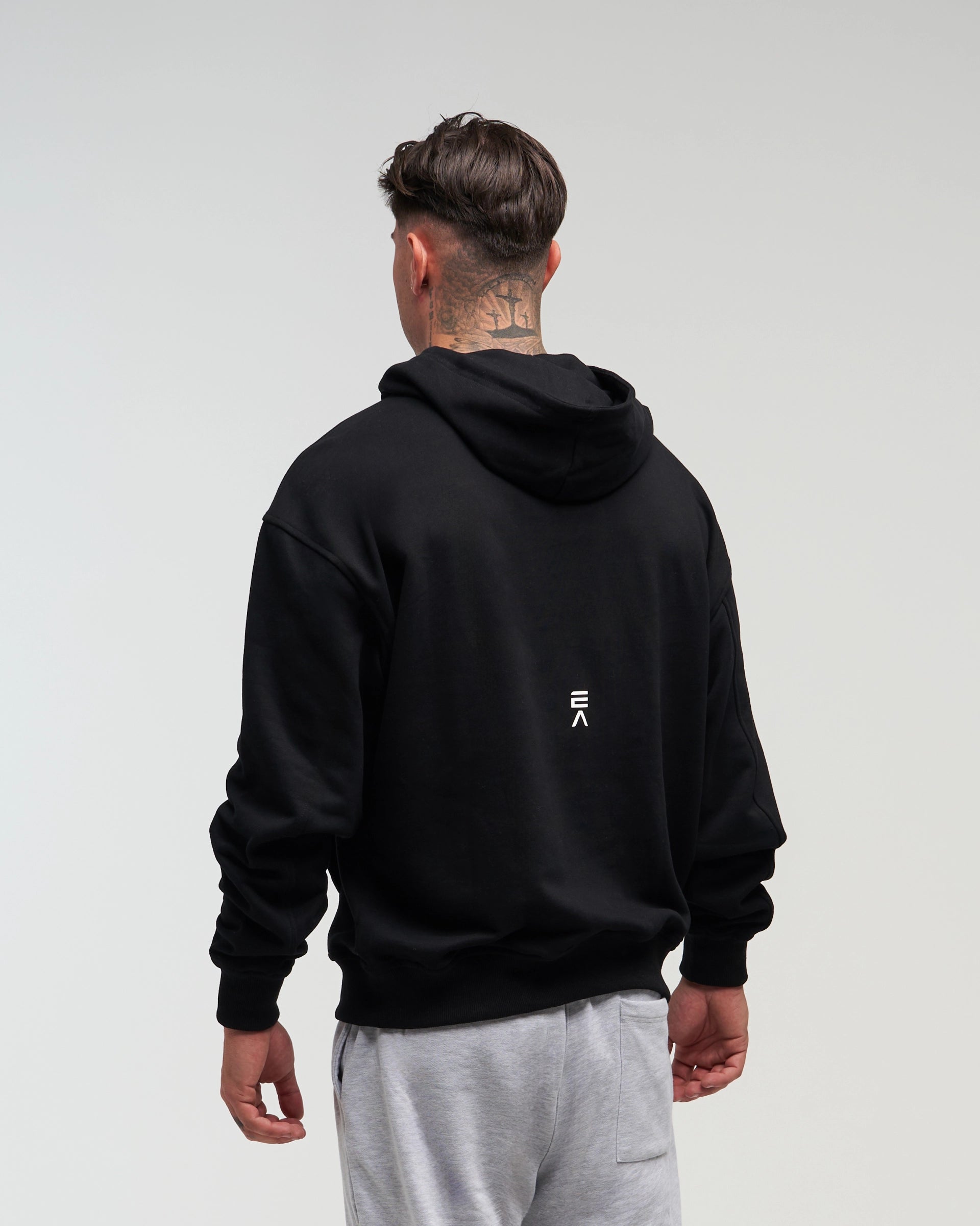 Back view of man wearing midnight black EVOActive Unisex Classic Pullover Hoody with logo visible on the garment against a bright background