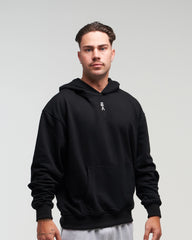 Front view of man in a slight side pose wearing midnight black EVOActive Unisex Classic Pullover Hoody against a bright background