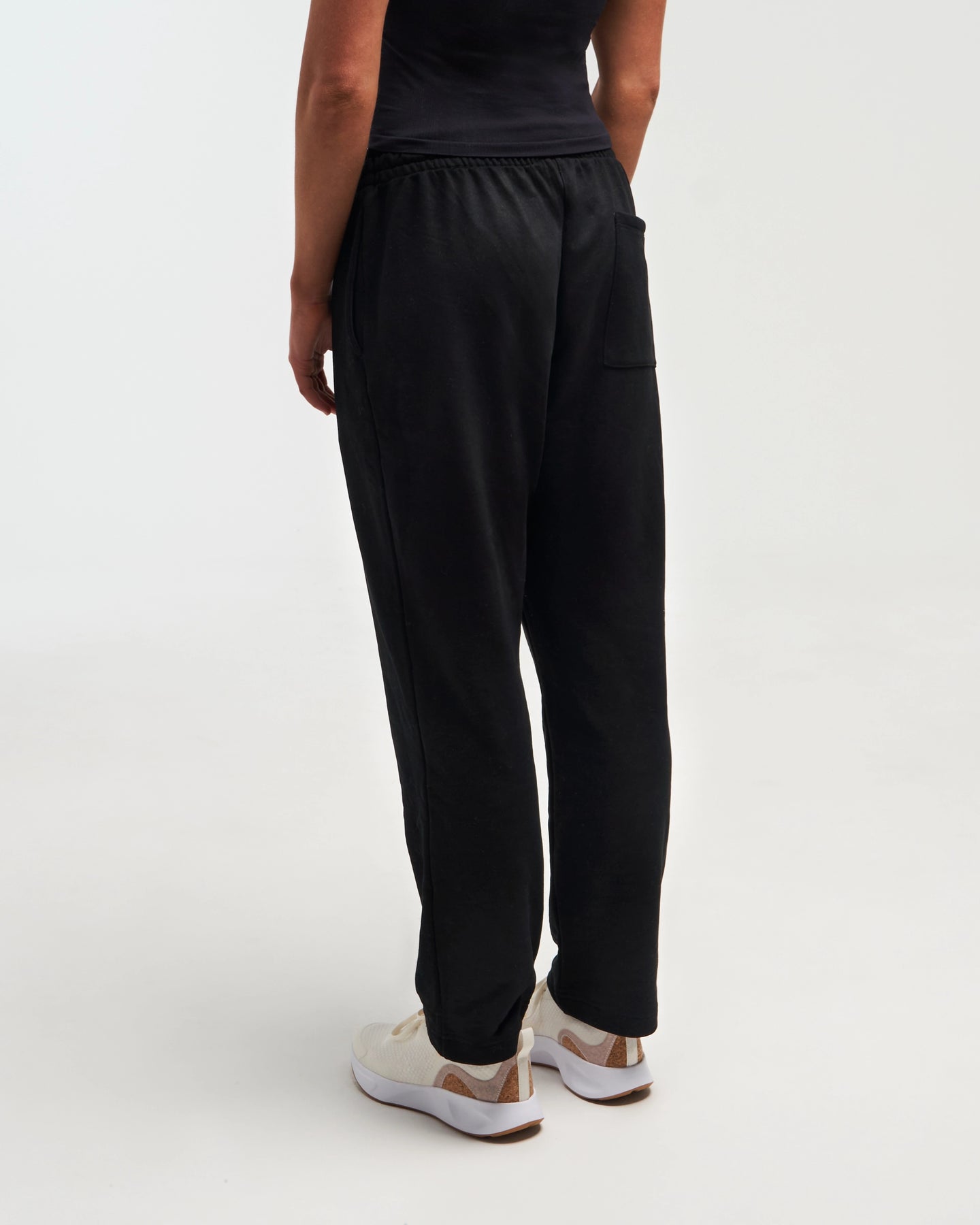 Lower-body view of woman wearing midnight black Unisex Classic Straight-Leg Jogger Pant against a bright background