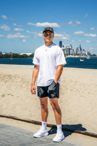 Full body view of man wearing Evo Ice white EVOActive Unisex Classic Tee standing on a beach