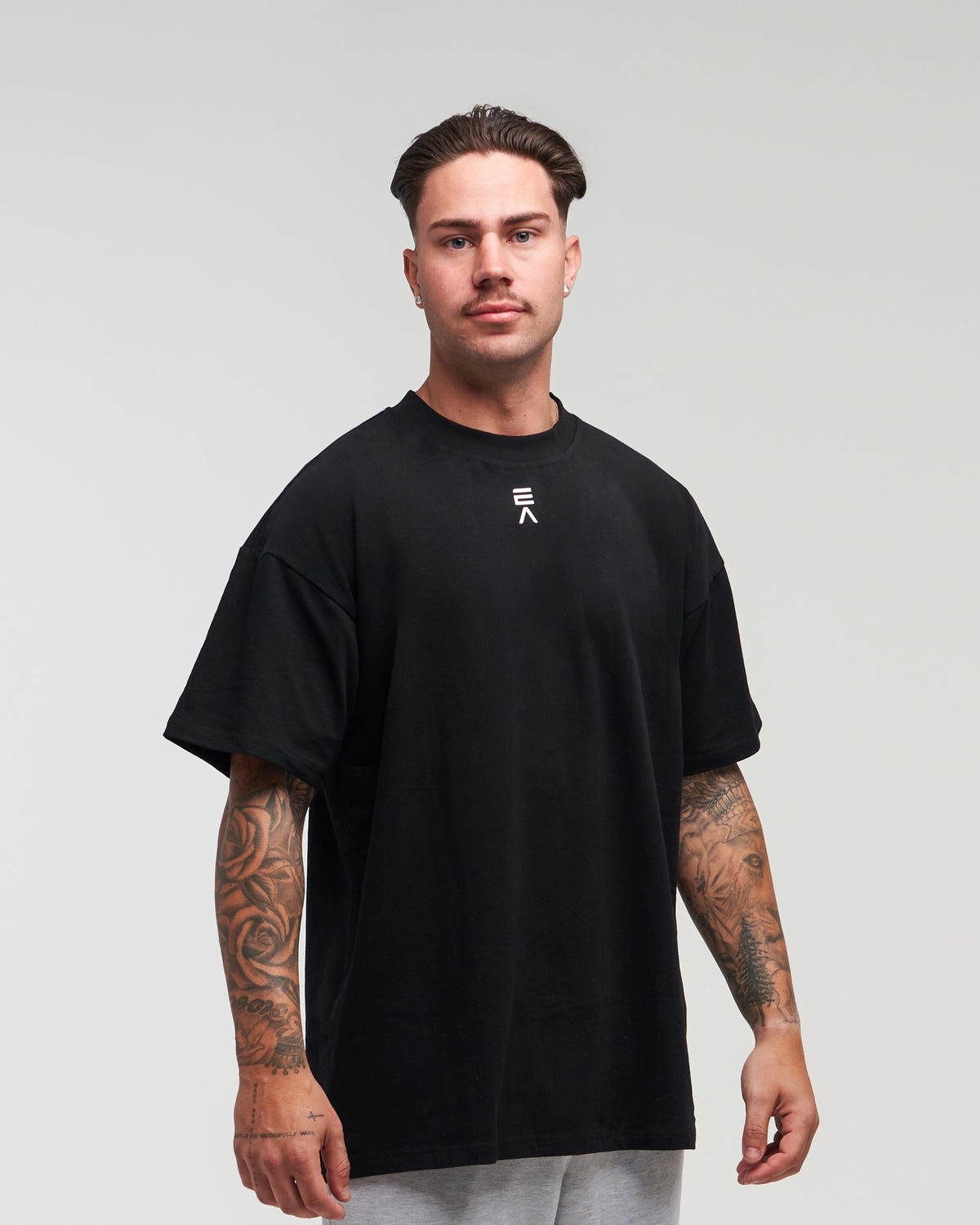 Close-up upper-body view of man wearing midnight black EVOActive Unisex Classic Tee with logo visible against a bright plain background