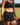  Mid-body front view of woman wearing midnight black EVOActive Women’s CoreRacer Short standing against running field with greenery in background and logo visible