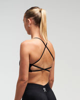 Back view of woman wearing midnight black Women’s Elevate Open Back Sports Bra in a slight side pose
