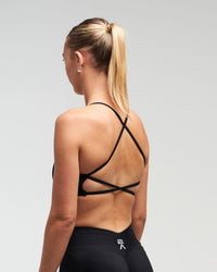 Back view of woman wearing midnight black Women’s Elevate Open Back Sports Bra in a slight side pose
