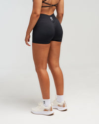 Back view of woman wearing midnight black EVOActive Women’s Elevate Short in a slight side pose with logo visible