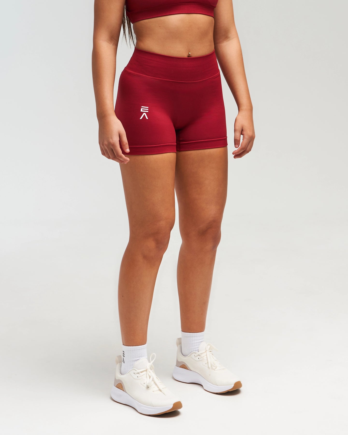 Front view of woman wearing red EVOActive Women’s Elevate Short in a slight side pose with logo visible
