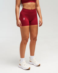 Front view of woman wearing red EVOActive Women’s Elevate Short in a slight side pose with logo visible