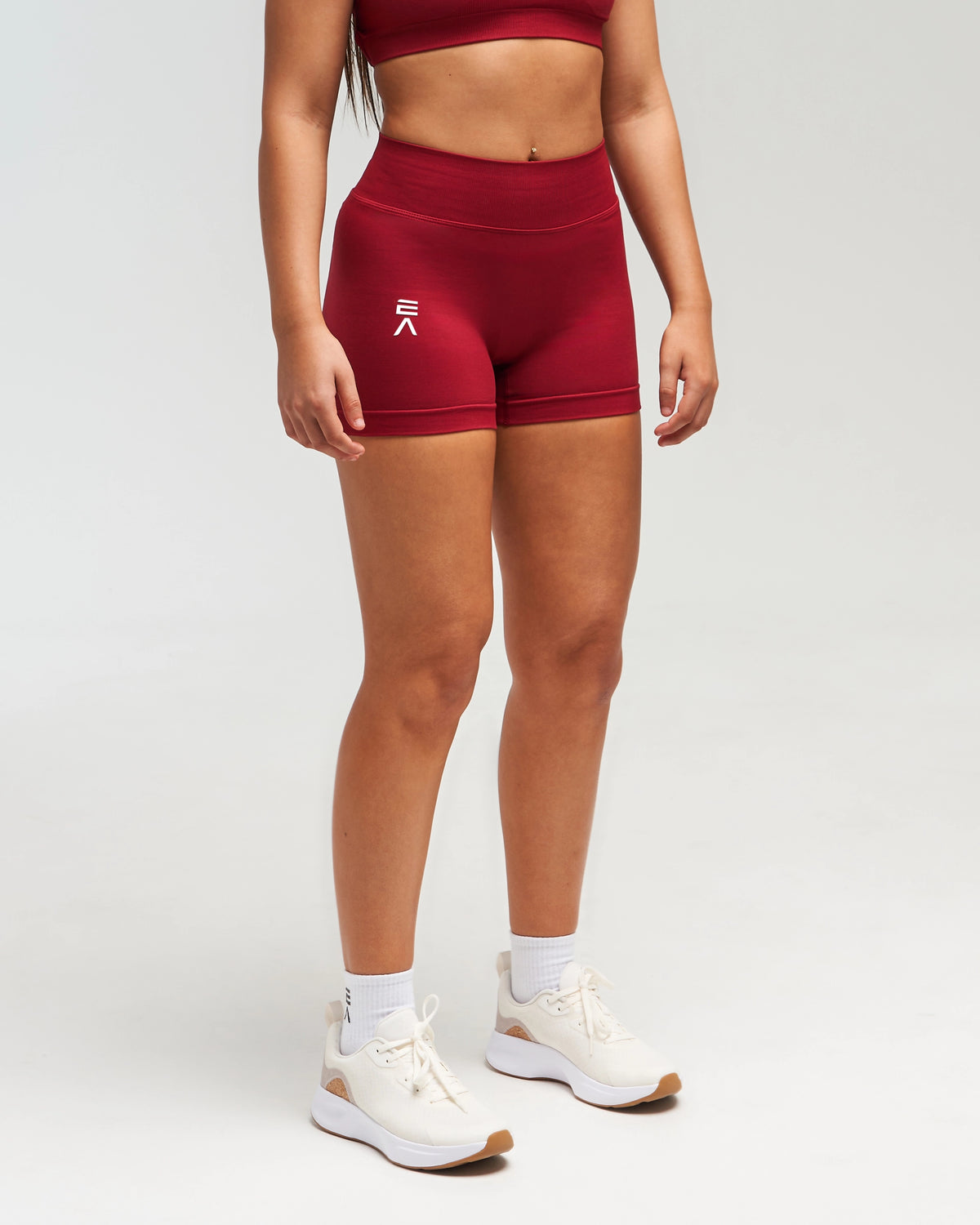 Front view of woman wearing red EVOActive Women’s Elevate Short in a slight side pose with logo visible
