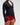 Mid-body view of woman wearing midnight black EVOActive Women’s Horizon Jacket with logo visible against bright background