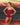 Woman wearing red EVOActive Women’s Motion Open Back Singlet standing between trackside chairs with running track visible behind