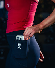 Side view of woman wearing midnight black EVOActive Women’s Motion Pocket Leggings with logo visible and mobile in pocket